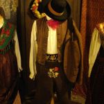 Traje antigo preservado na região de Primiero. Estão presentes o patel bordado, o colete, o cinturão de couro e o lenço no pescoço, além do chapéu.